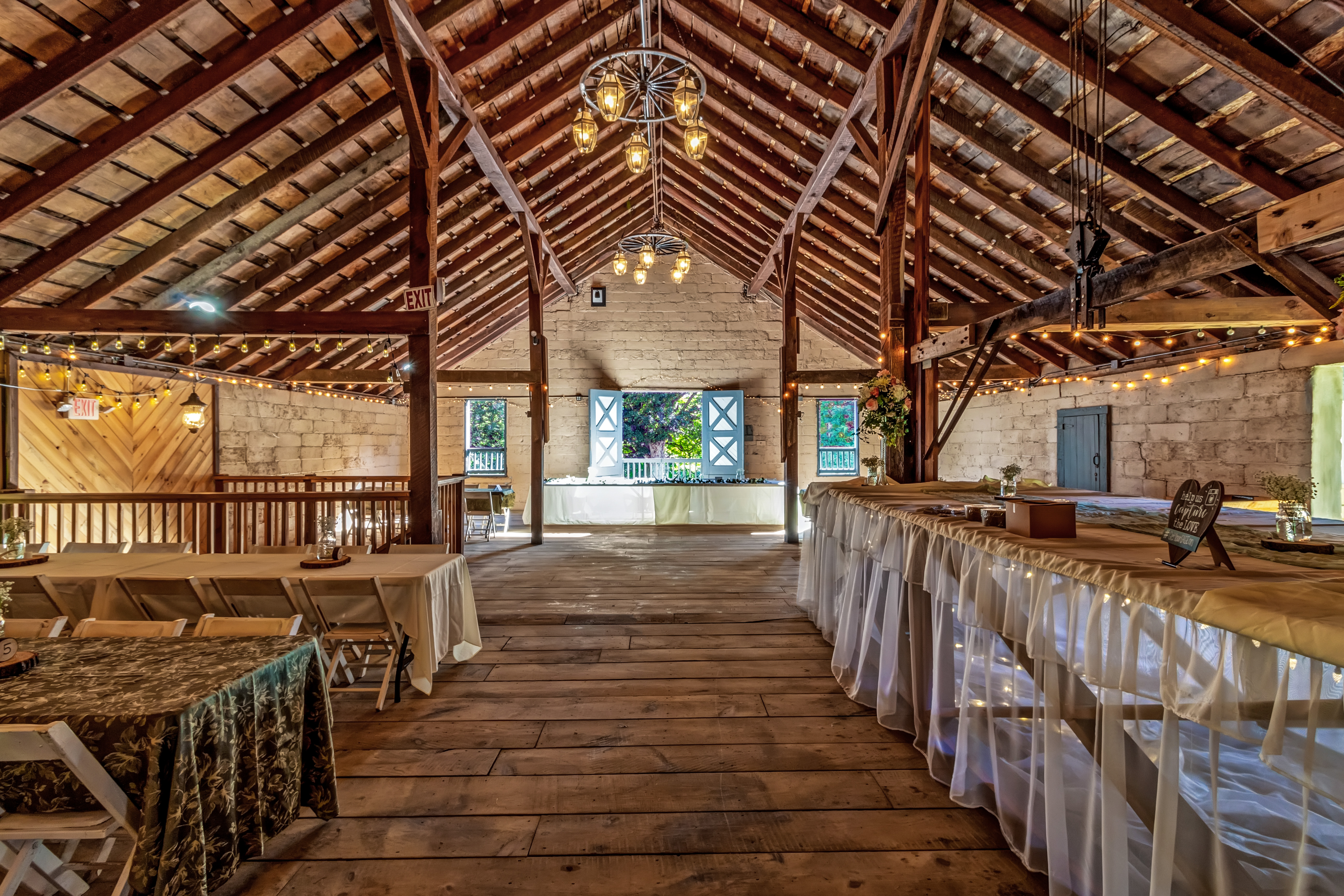 The RED House barn — full interior with wagon wheel chandeliers, string lights and stone walls