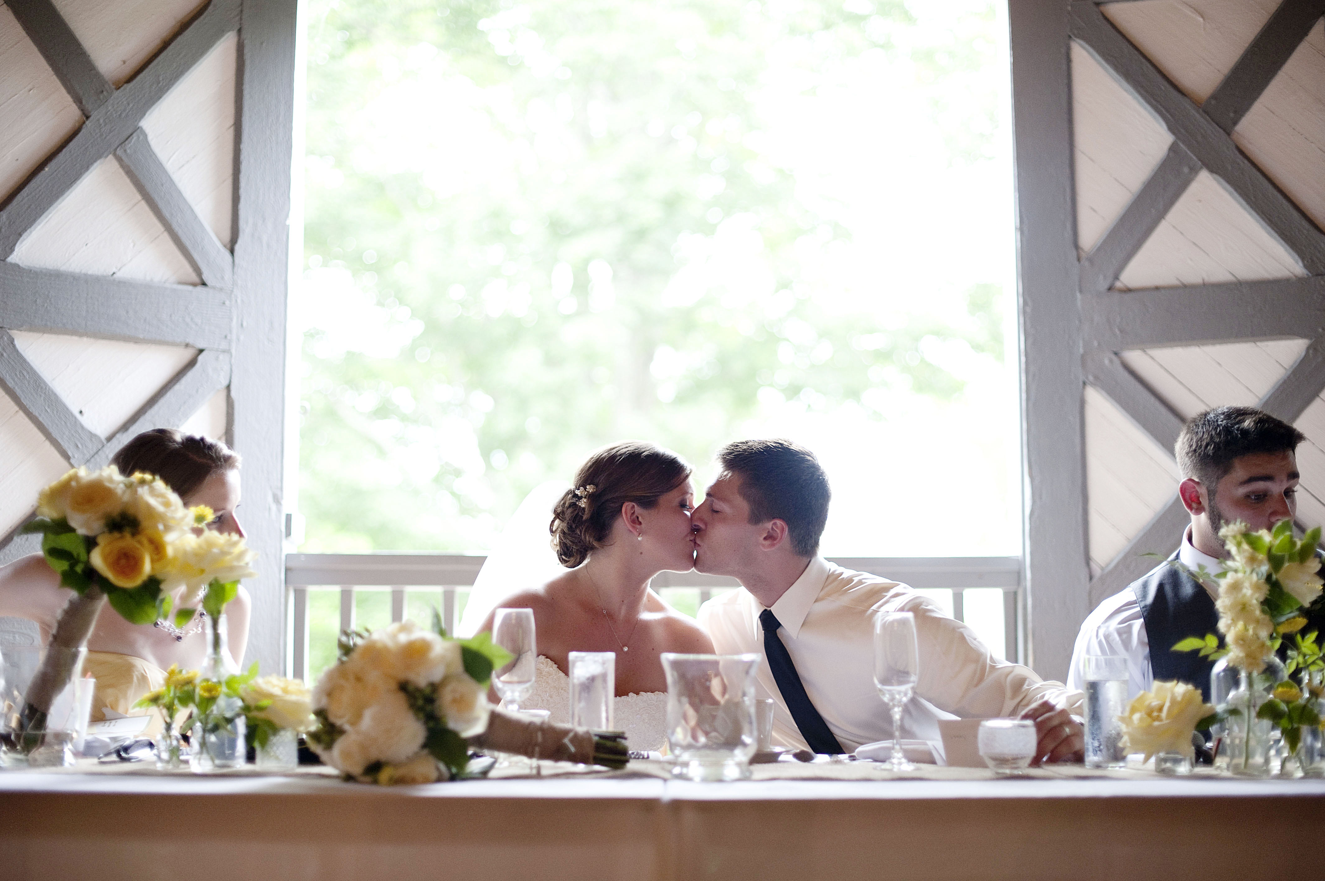 Bride and groom kissing in a rowboat under a willow tree on the RED House grounds