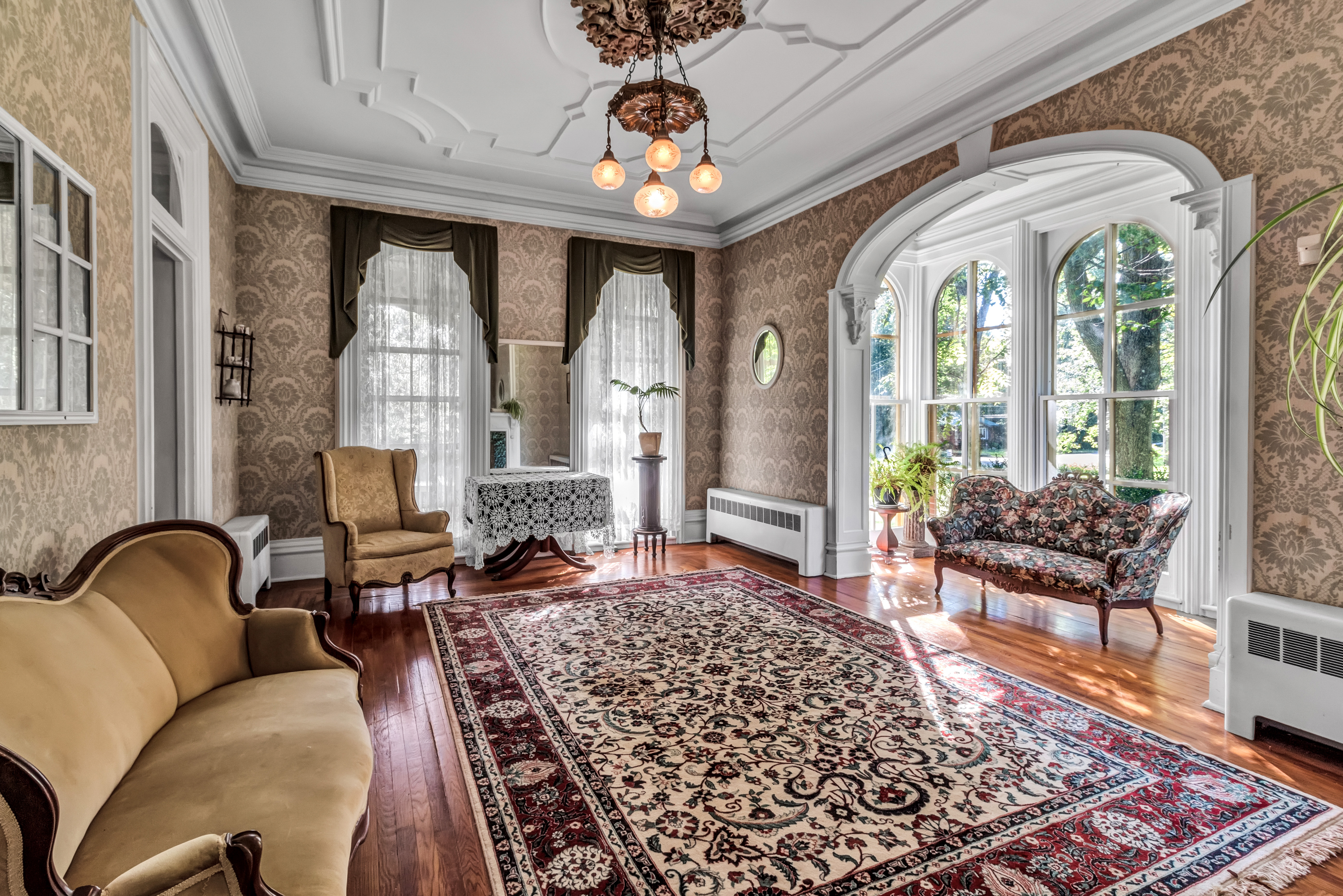 The RED House Victorian manor parlour — original plasterwork, hardwood floors and arched windows